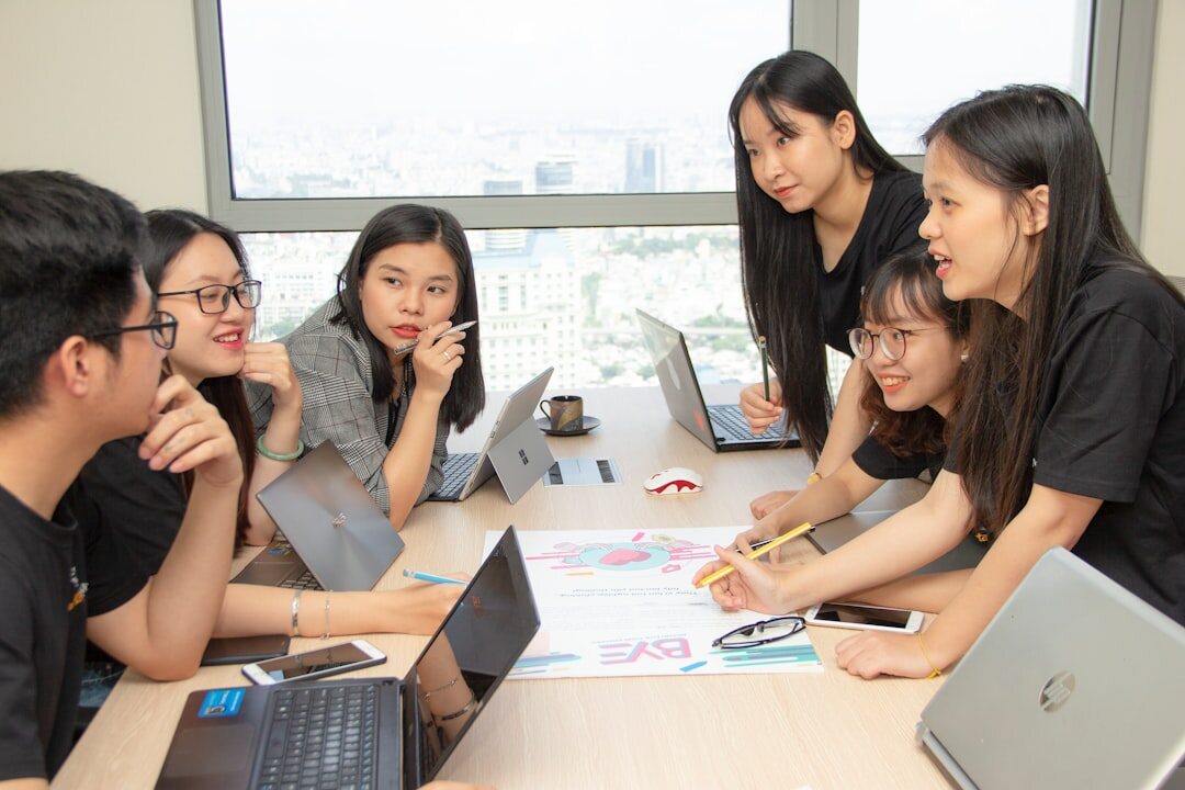 Team of organizers meeting around a table with laptops and notes